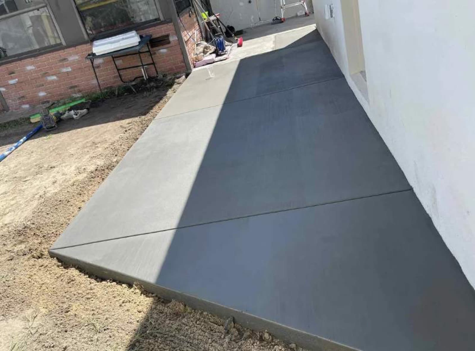 Freshly poured and finished concrete slab next to brick wall in Central Florida — Firsthand Lawn and Landscape
