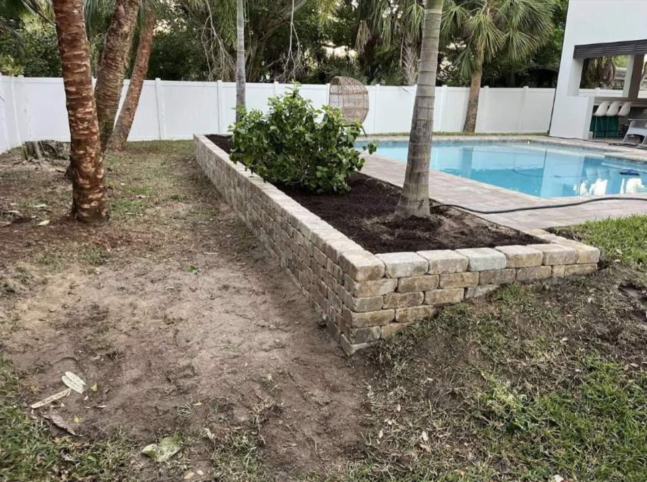 Stacked-stone retaining wall around pool-side plant bed in Central Florida — Firsthand Lawn and Landscape