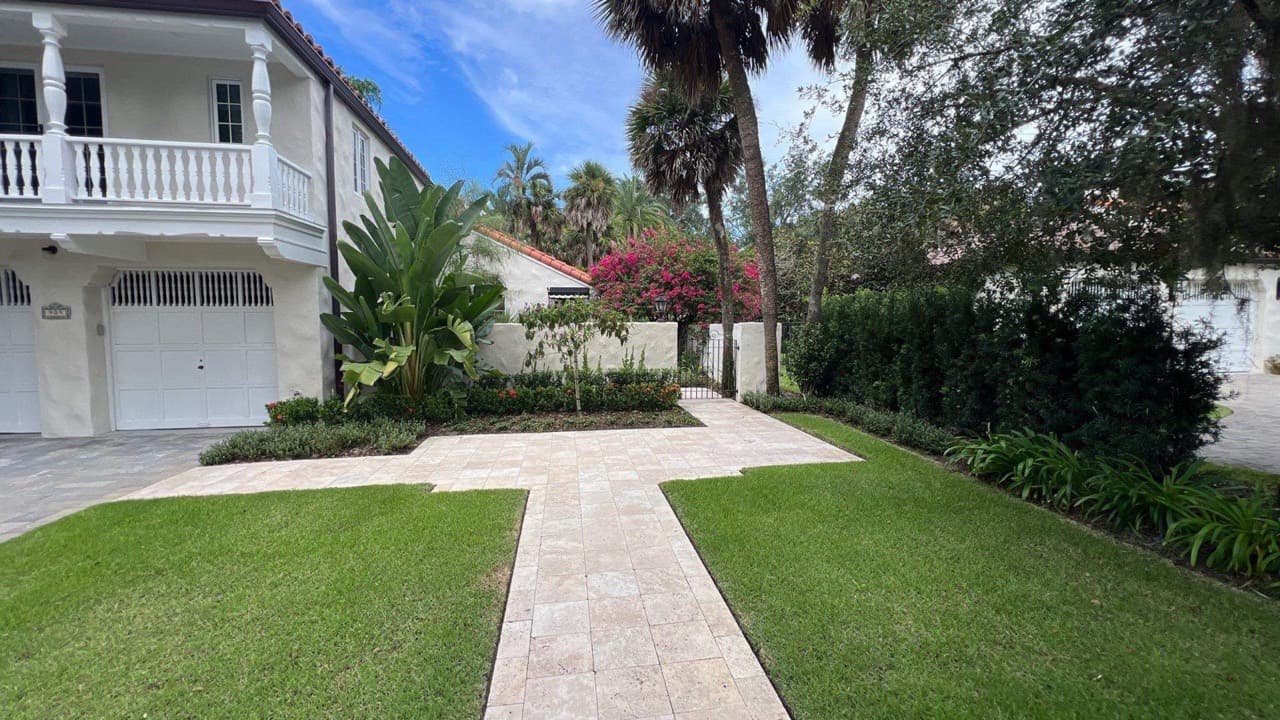 Two-story Mediterranean home with travertine walkway, palms, and bougainvillea in Central Florida — Firsthand Lawn and Landscape